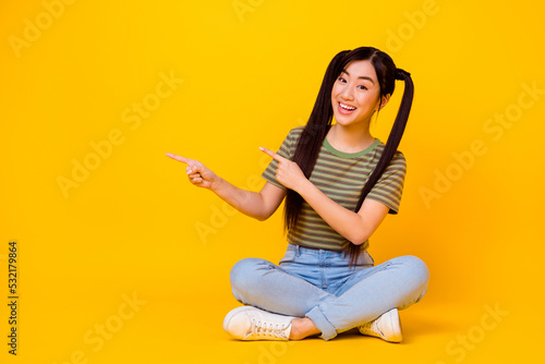 Obraz na plátně Photo of young attractive woman sitting on floor point fingers blank space show