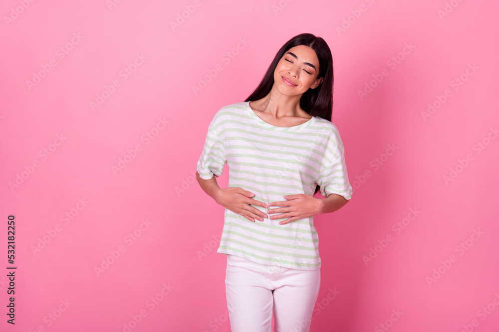Photo of adorable satisfied person closed eyes arms touch stomach isolated on pink color background Photo of adorable satisfied person closed eyes arms touch stomach isolated on pink color background
