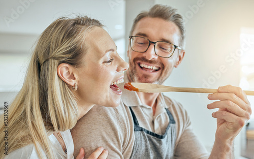 Quadro su tela Happy couple cooking, tasting spoon of food and meal, lunch and dinner in kitchen at home