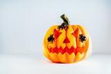 Spooky halloween orange pumpkin, Jack O Lantern with spiders on it on the white background with copy space. Happy Halloween decor concept. Festive postcard. Selective focus
