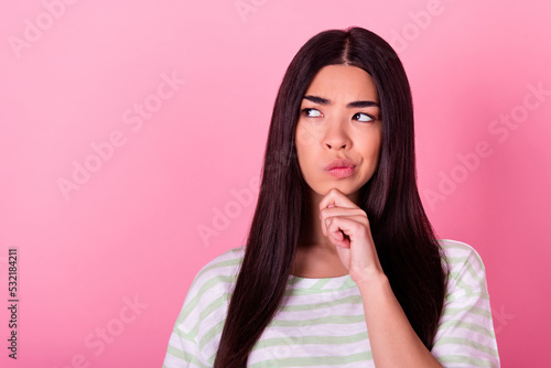 Portrait of minded malaysian person arm touch chin look interested empty space hesitate isolated on pink color background
