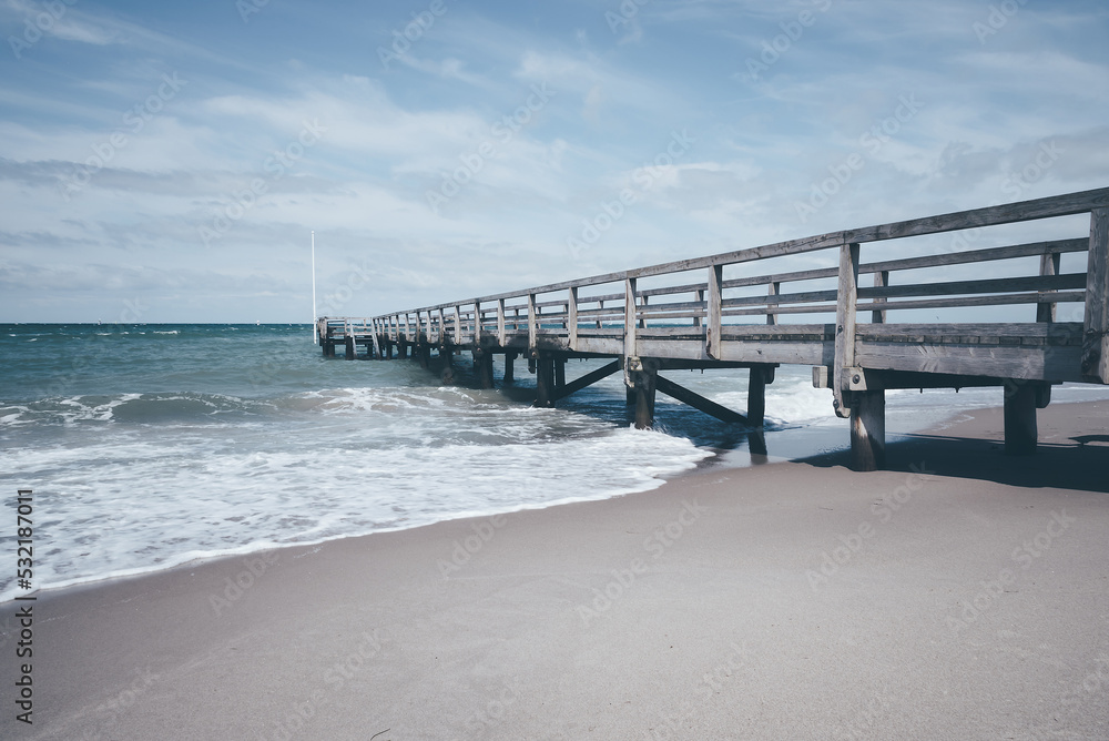Obraz premium wooden pier at rough baltic sea on dark and windy day, German seaside