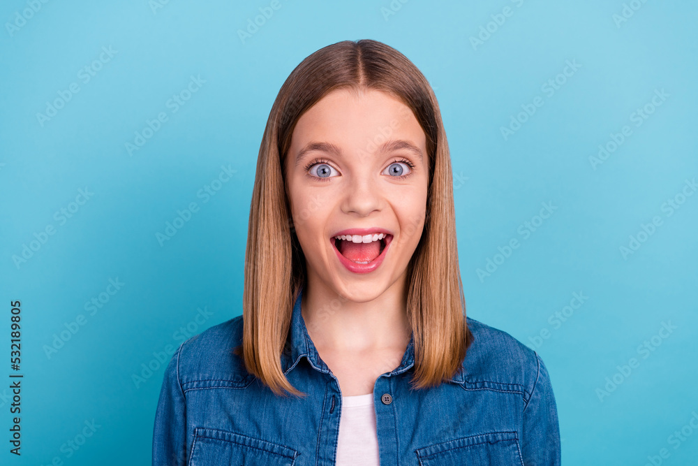 Photo of impressed small blond girl look empty space wear jeans shirt isolated on blue color background Photo of impressed small blond girl look empty space wear jeans shirt isolated on blue color background
