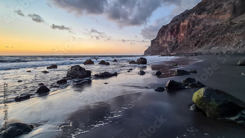Scenic view during sunset on volcanic black sand beach Playa del Ingles in Valle Gran Rey, La Gomera, Canary Islands, Spain, Europe. Massive cliffs of the La Mercia range. Smooth waves sweeping rocks © Chris