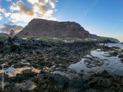 Panoramic view on massive sharp cliffs and mountains in village Valle Gran Rey, La Gomera, Canary Islands, Spain, Europe. Vista on beach Playa Charco del Conde with shoreline of volcanic black rocks photo