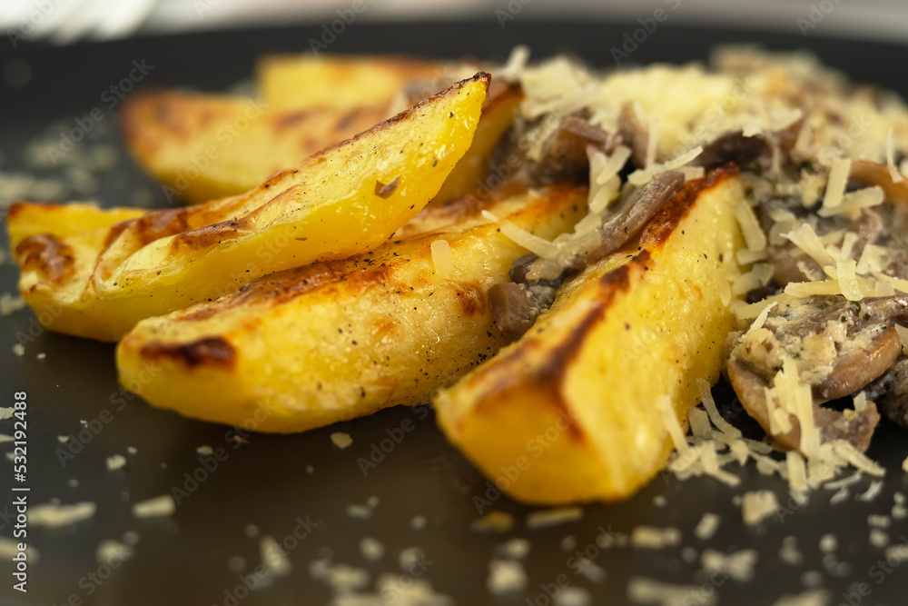 Close up of plate of baked potatoes with mushrooms sprinkled with permesan cheese. Champignons. Food Close up of plate of baked potatoes with mushrooms sprinkled with permesan cheese. Champignons. Food