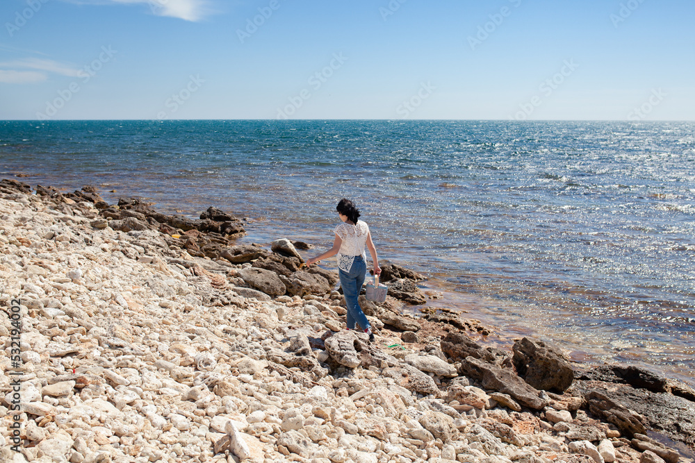 Girl collects driftwood on the seashore