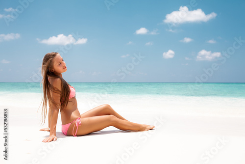 Young attractive blonde girl with perfect sport body in bikini on the tropical summer beach