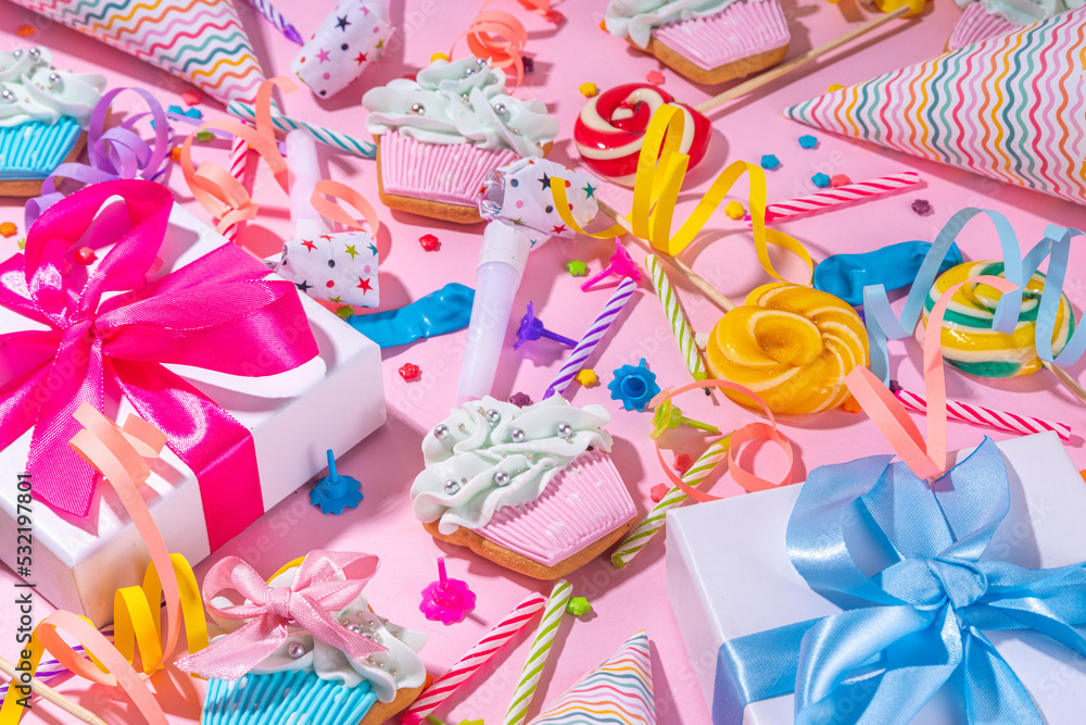 Fototapeta premium Happy birthday greeting card background. Flatlay with colorful holiday tools - birthday party caps, blowers, gift boxes , balloons, steamers, candles, on pink background copy space