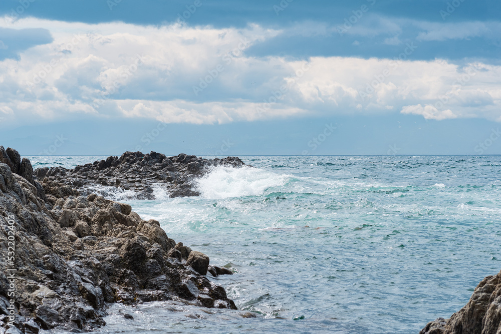 coastal rocks, consisting of columnar basalt, among the sea surf, Cape Stolyuchy on the island of Kunashir