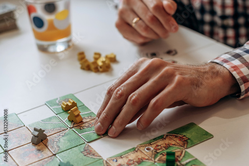 A group of young people play board games at home in the kitchen.Hands close-up.Time together.Stay home,board games concept.Selective focus.