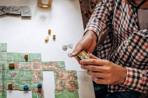 A group of young people play board games at home in the kitchen.Hands close-up.Time together.Stay home,board games concept.Selective focus.