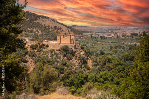 The Kasbah castle from the Middle Atlas and the Tadla plain of Morocco protecting and overlooking the Moroccan city of Beni Mellal-Jenifra under an orange sky. Concept Morocco, castle, city, landscape photo
