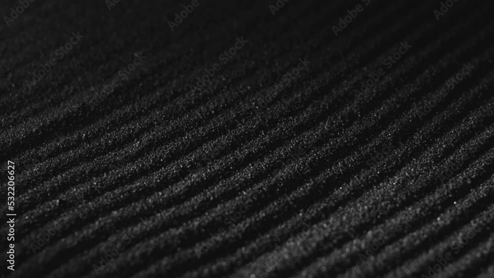 Black sand surface with paths. Abstract textured background. Dark dust falling, covering ground. Close-up Black sand surface with paths. Abstract textured background. Dark dust falling, covering ground. Close-up