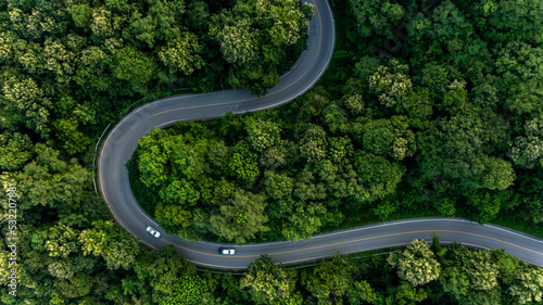 Aerial top view asphalt road in forest with car motion blur, Winding road through the forest, Car drive on the road between green forest.