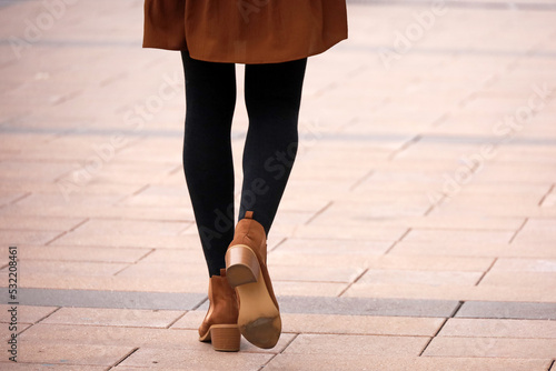 Female legs in black warm tights and brown shoes. Slim girl walking on a street, fashion in autumn city photo