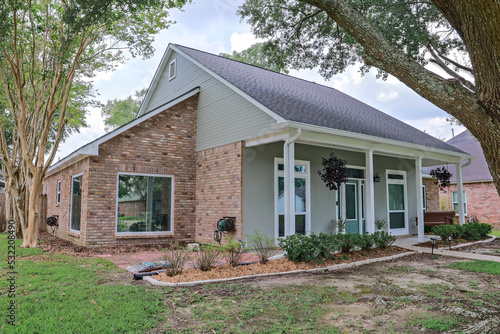 An angled front and side view of an Acadian renovated home with columns, sidewalks and a colorful front door recently purchased with the changing real estate market