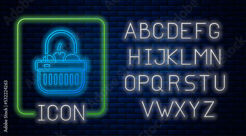 Glowing neon Shopping basket and food icon isolated on brick wall background. Food store, supermarket. Neon light alphabet. Vector