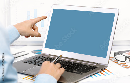 Finance and business concept. Hand pointing at the mockup screen. laptop on financial graphs on desk. Female small business. Accounting budgeting loans or market analysis. Business growth