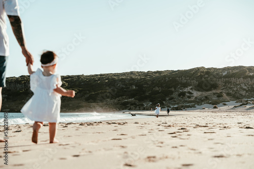 Padre e hija paseando por la orilla de la playa agarrados de la mano . photo
