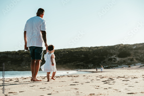 Padre e hija caminando por la orilla de la playa al fondo dunas de Bolonia tarifa. photo