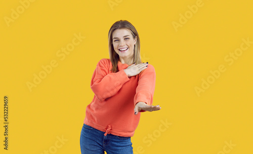 Happy dancing girl. Studio shot of joyful camp counselor or college student. Good looking young woman smiling at camera and dancing macarena to cheerful music standing isolated on colour background photo