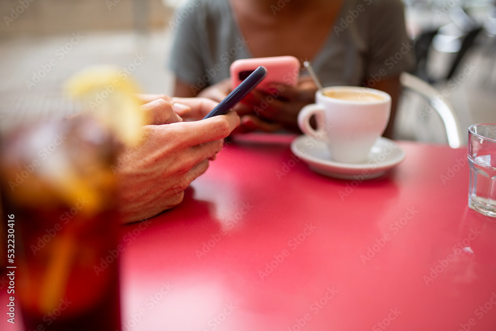 Two diverse friends using mobile phone at coffee shop