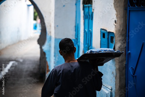 Hombre árabe portando comida diaria pasando por arco musulmán 