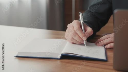 Close-up of a businessman's hand taking notes and planning. Notepad on the desk in the office of a successful man.