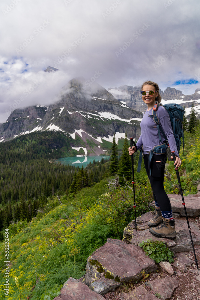 Woman hiker takes a moment to enjoy the scenery along the Grinnell Glacier Hike in Glacier National Park Montana