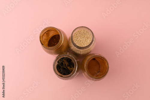 Spices in glass jars on a pink background