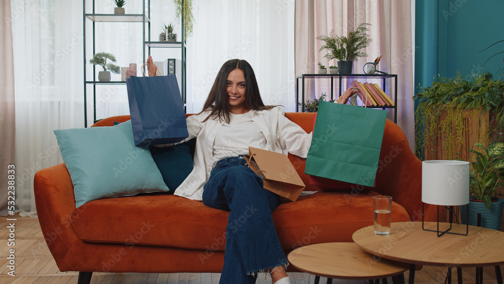 Portrait of caucasian adult girl happy shopaholic consumer came back home after shopping sale with bags. Young woman satisfied received parcels from online order at modern home apartment living room Portrait of caucasian adult girl happy shopaholic consumer came back home after shopping sale with bags. Young woman satisfied received parcels from online order at modern home apartment living room