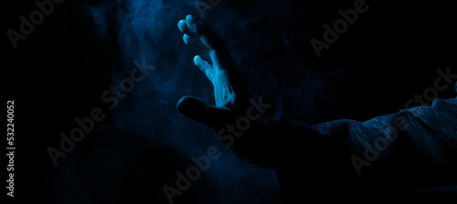 A scary hand on dark background. Mysterious composition. Fortune teller, mind power, prediction, halloween concept. Wide angle horizontal wallpaper or web banner. Mockup for your logo.