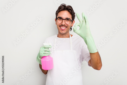 Young cleaner hispanic man isolated on white background cheerful and confident showing ok gesture.