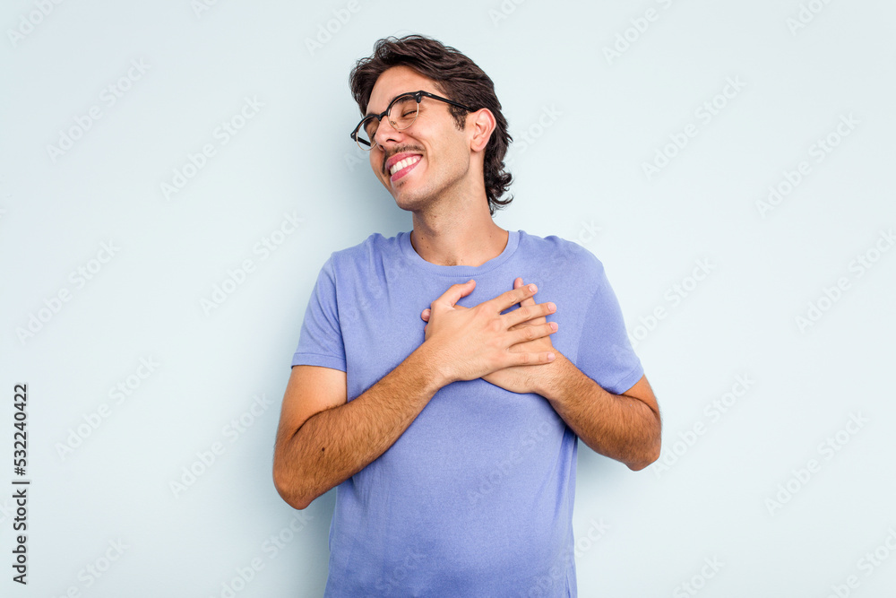 Young hispanic man isolated on blue background has friendly expression, pressing palm to chest. Love concept. Young hispanic man isolated on blue background has friendly expression, pressing palm to chest. Love concept.