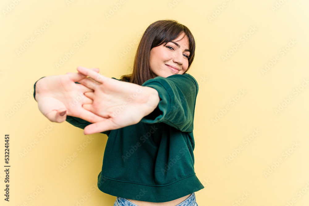 Fototapeta premium Young caucasian woman isolated on yellow background stretching arms, relaxed position.