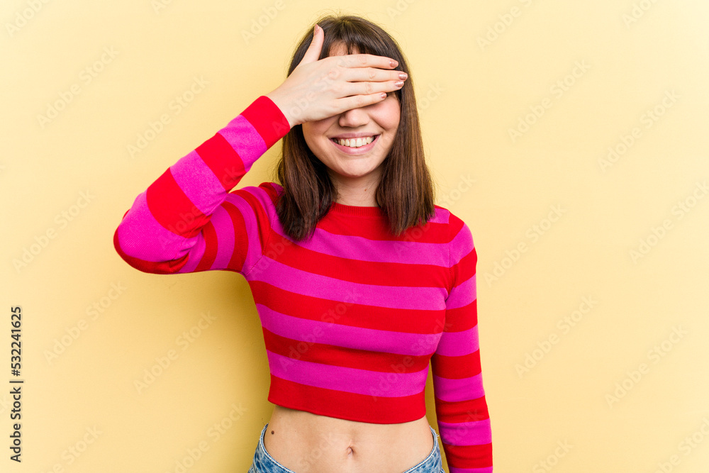 Young caucasian woman isolated on yellow background covers eyes with hands, smiles broadly waiting for a surprise. Young caucasian woman isolated on yellow background covers eyes with hands, smiles broadly waiting for a surprise.