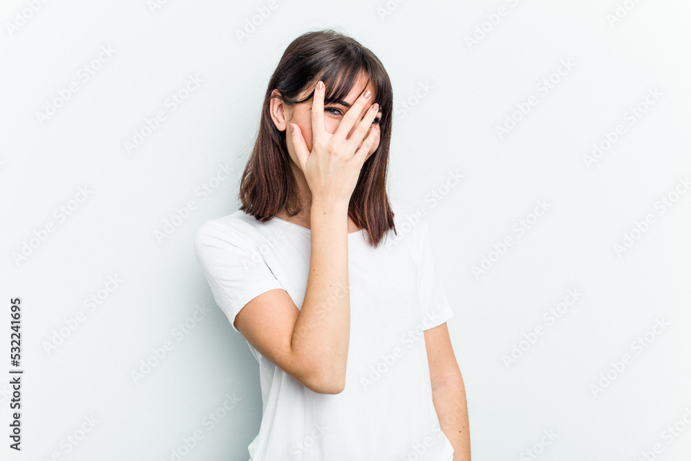 Young caucasian woman isolated on white background blink at the camera through fingers, embarrassed covering face. Young caucasian woman isolated on white background blink at the camera through fingers, embarrassed covering face.