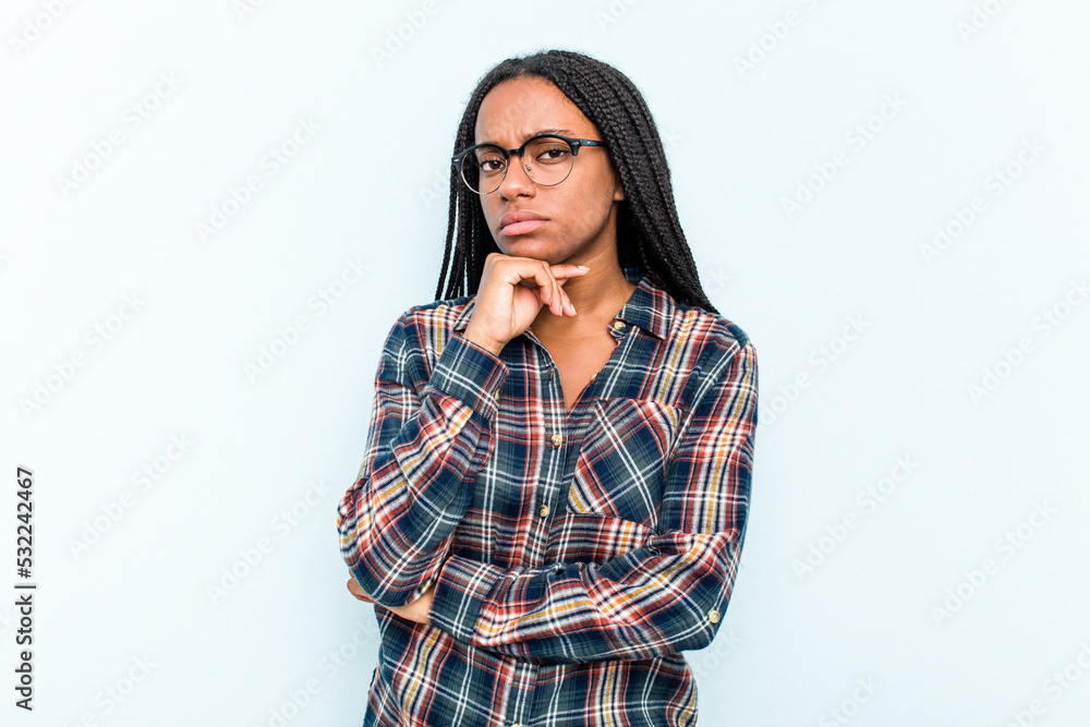 Young African American woman with braids hair isolated on blue background suspicious, uncertain, examining you. Young African American woman with braids hair isolated on blue background suspicious, uncertain, examining you.