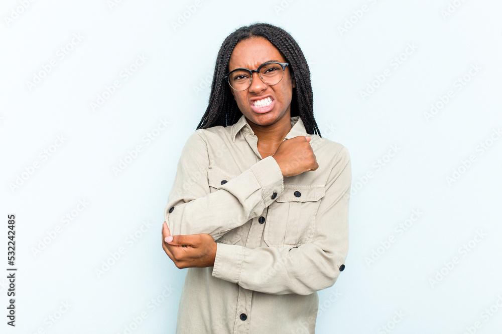 Young African American woman with braids hair isolated on blue background massaging elbow, suffering after a bad movement. Young African American woman with braids hair isolated on blue background massaging elbow, suffering after a bad movement.