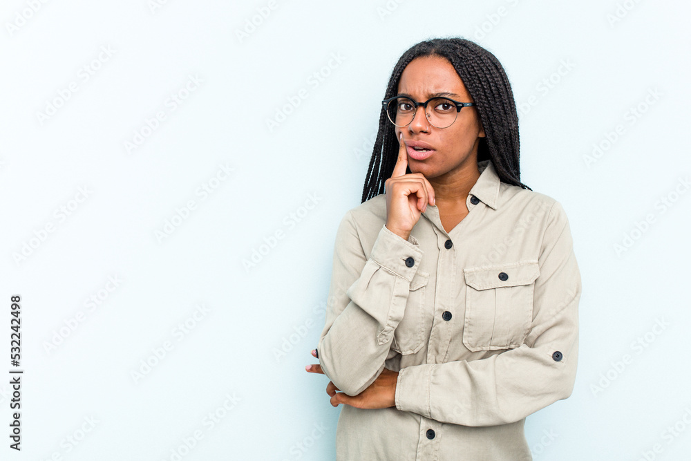 Young African American woman with braids hair isolated on blue background looking sideways with doubtful and skeptical expression. Young African American woman with braids hair isolated on blue background looking sideways with doubtful and skeptical expression.