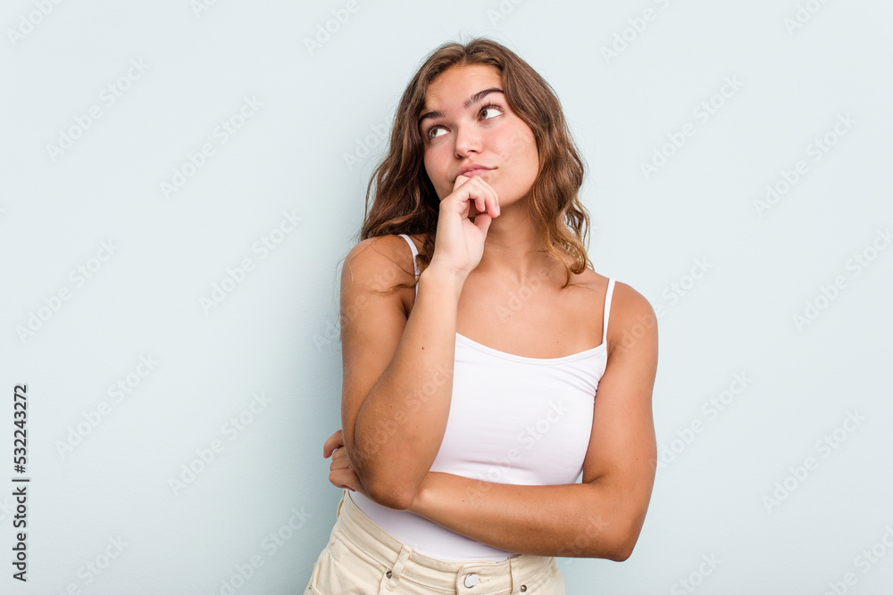 Young caucasian woman isolated on blue background thinking and looking up, being reflective, contemplating, having a fantasy. Young caucasian woman isolated on blue background thinking and looking up, being reflective, contemplating, having a fantasy.