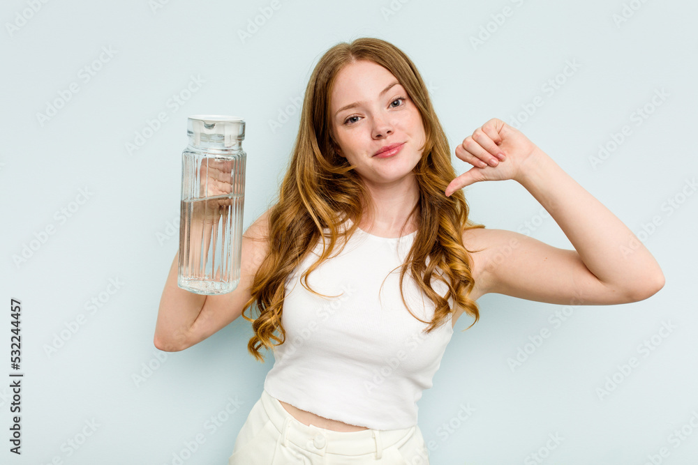 Young caucasian woman holding jar of water isolated on blue background feels proud and self confident, example to follow. Young caucasian woman holding jar of water isolated on blue background feels proud and self confident, example to follow.
