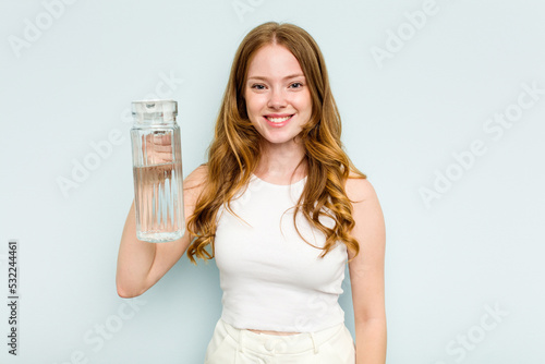 Young caucasian woman holding jar of water isolated on blue background happy, smiling and cheerful.