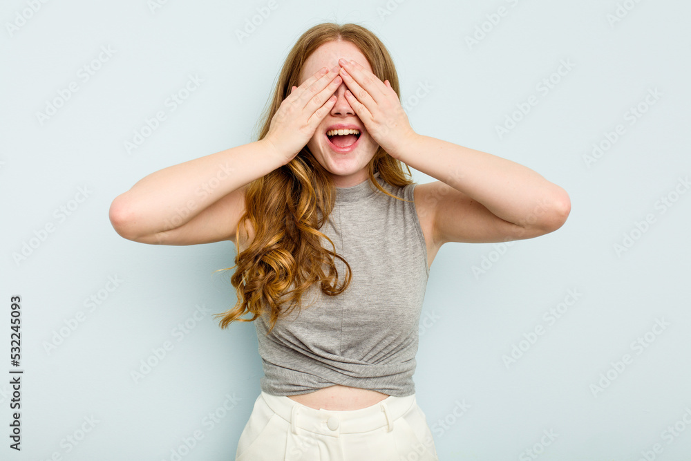 Young caucasian woman isolated on blue background covers eyes with hands, smiles broadly waiting for a surprise. Young caucasian woman isolated on blue background covers eyes with hands, smiles broadly waiting for a surprise.