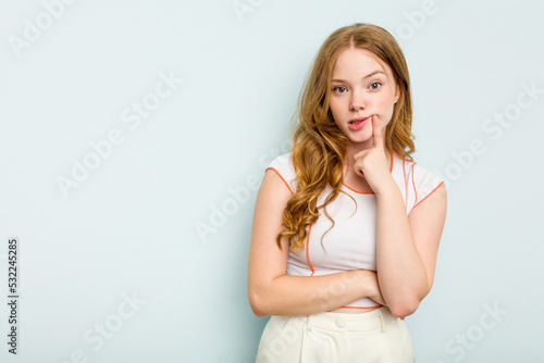 Young caucasian woman isolated on blue background looking sideways with doubtful and skeptical expression.