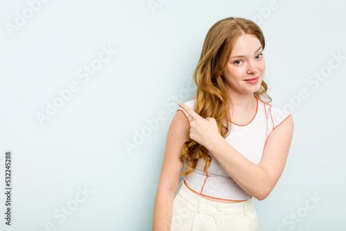 Young caucasian woman isolated on blue background smiling and pointing aside, showing something at blank space.
