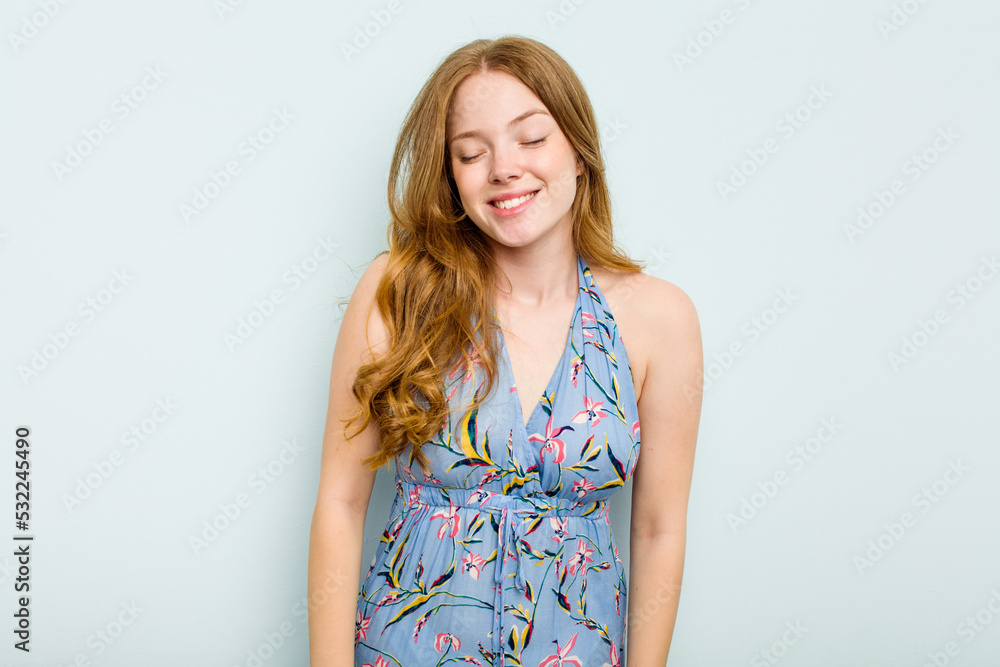 Young caucasian woman isolated on blue background laughs and closes eyes, feels relaxed and happy. Young caucasian woman isolated on blue background laughs and closes eyes, feels relaxed and happy.