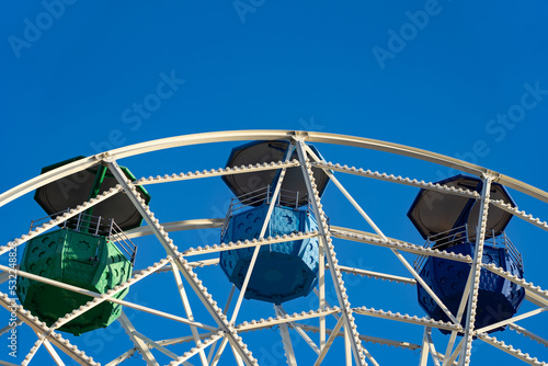 A close-up shot of a colorful ferris wheel against blue sky. Holiday, vacation concept