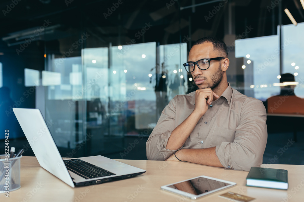 Thinking Hindu businessman in glasses, male programmer developer working inside office of modern product IT company, entrepreneur at work with laptop. Thinking Hindu businessman in glasses, male programmer developer working inside office of modern product IT company, entrepreneur at work with laptop.